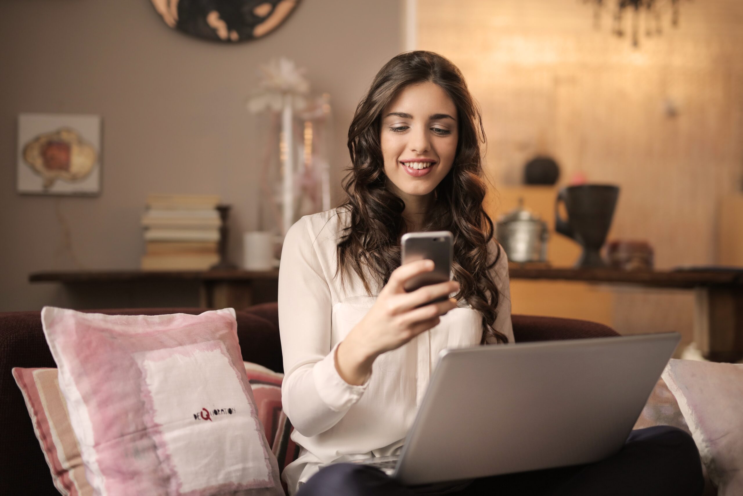 woman-sitting-on-sofa-while-looking-at-phone-with-laptop-on-920382 Backup for Small UK Business: Freelancers as well as SMBs